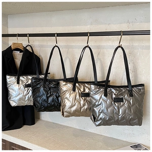 Quilted puffer tote bags in silver, black, gold, and grey hanging on a metal rack