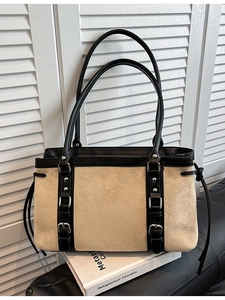 Vintage beige suede tote bag with black leather trim and silver buckles on books