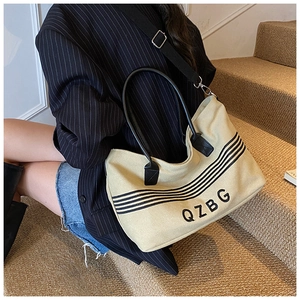 Detail of canvas tote bag showing black QZBG logo and decorative stripes on beige fabric