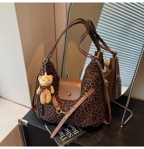 Detail of leopard print tote bag with brown leather flap and plush bear charm
