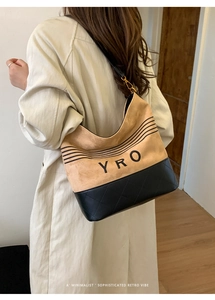 Detail of quilted leather bucket bag with YRO branding worn by a model in interior setting