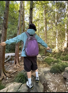 Outdoor view of purple hiking backpack with side reflective strips and dual zippers