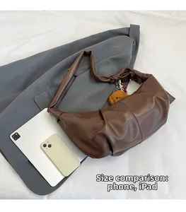 Brown leather crossbody bag detail compared to an iPad and phone for scale