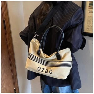 Detail of striped canvas tote bag with black wide strap and logo for daily casual use