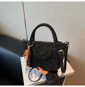 Detail of vintage black matte crossbody bag with top handle and wooden bead charm