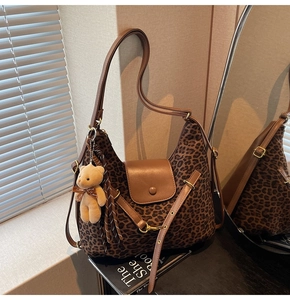 Detail of leopard print tote bag with brown leather flap and cute plush bear charm