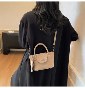 Detail view of beige crossbody bag featuring wooden bead charms and textured matte leather