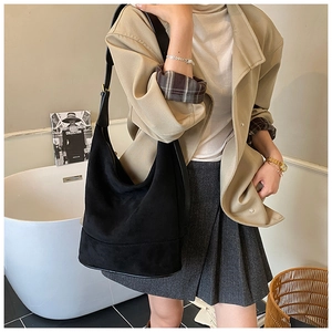Detail of a large black suede hobo bag with a gold metal buckle for daily commute