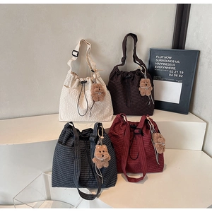 Detail of multi-color bucket bags with drawstring closure and teddy bear pendant