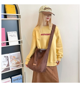Close-up of brown suede drawstring tote bag with our love label on model in casual outfit