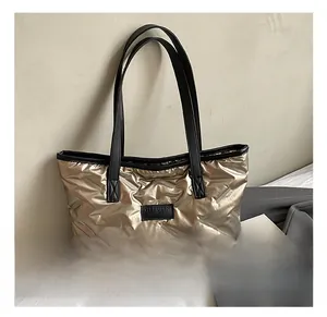 Close-up of champagne gold quilted tote bag featuring a black leather logo and straps