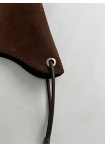Macro shot of silver metal eyelet and stitching on dark brown suede bucket bag strap