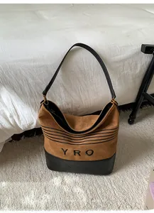 Detail of suede and quilted leather tote with YRO logo and golden metal hardware