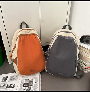 Detailed view of color-block nylon backpacks in orange and grey for travel or school