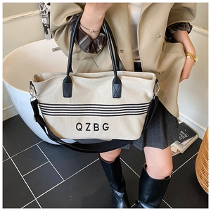 Detail of canvas tote bag showing striped pattern, logo print, and black nylon strap