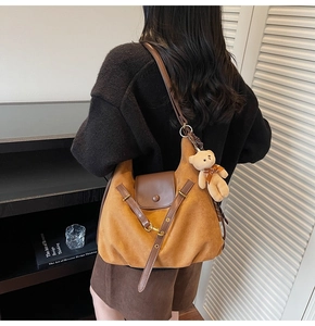 Brown suede tote bag with leather flap and plush bear charm shown on model