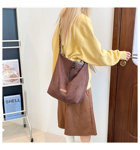 Detail of coffee brown suede bucket bag with drawstring closure and custom leather label