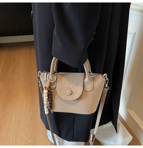 Detail view of khaki PU leather crossbody bag with wooden bead charm and flap buckle