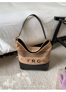 Detail of the YRO tote bag showing tan suede texture and black quilted leather base