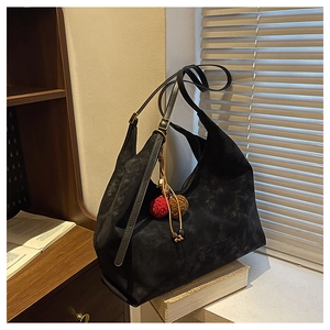 Détail du sac cabas en daim noir avec boucles dorées et breloque en peluche douce