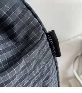 Detail of dark grey checkered canvas fabric and sewn brand label on a large tote bag