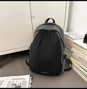 Detail of the gray and black nylon backpack featuring a reinforced top handle and large pocket