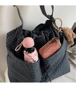 Detail view of large checkered canvas bucket bag with side pockets for umbrella and wallet