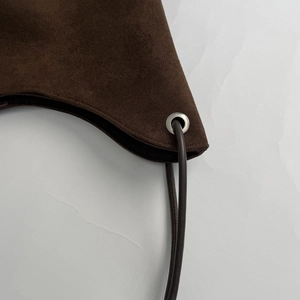 Detail of dark brown suede tote bag showing stitching and silver metal eyelet hardware