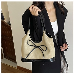 Detail of beige and black bucket bag with leather bow and textured matte finish