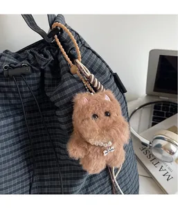 Brown plush dog keychain with pearl necklace on gray checkered canvas backpack detail
