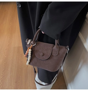 Detail of vintage brown textured crossbody bag with colorful beads and leather handles