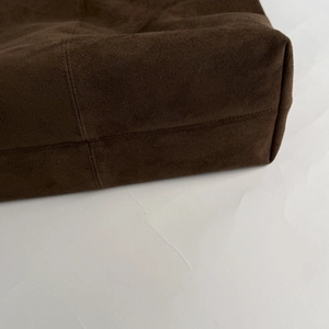 Macro view of stitching and suede texture on a vintage dark brown tote bag corner