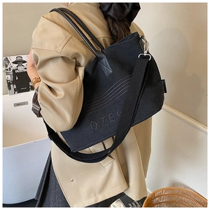 Detail view of large black canvas tote bag with letter embroidery and crossbody strap