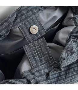 Close-up of silver magnetic closure and grid-textured fabric on dark grey bucket bag