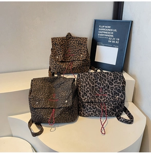 Detailed close-up of leopard print backpacks with red take it easy embroidery and drawstrings