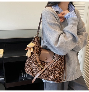 Detail of leopard print tote bag with brown leather flap and cute plush bear charm