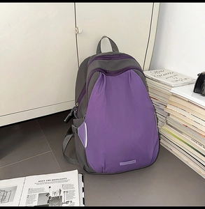 Detail of a purple and grey contrast nylon backpack leaning against a locker in a campus setting