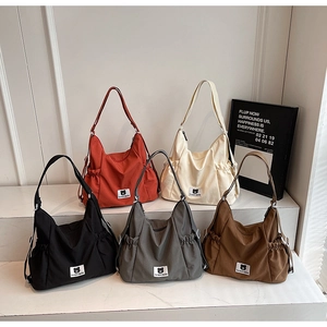 Detail showing five colors of large canvas tote bags with bear patch and drawstring pockets