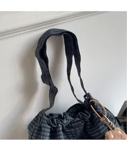 Close-up of wide checkered shoulder strap and drawstring closure on bucket bag