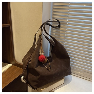 Gros plan d'un grand sac cabas en daim marron foncé avec logo embossé et pendentif peluche
