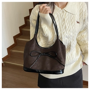 Detail of dark brown suede bucket bag with black bow decoration and leather handle