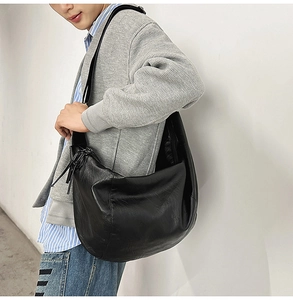 Détail d'un grand sac bandoulière noir minimaliste en cuir souple avec vue de profil