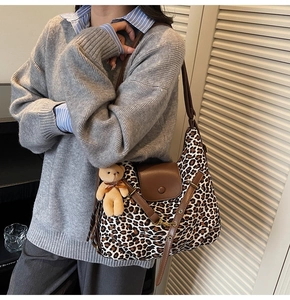 Leopard print tote bag with brown leather straps and plush bear charm on model