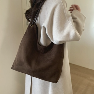 Detail of large brown suede hobo tote bag featuring metallic eyelet and matte texture