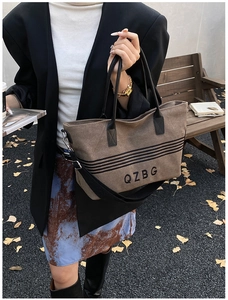 Detail of striped canvas tote with adjustable strap and QZBG print in autumn setting