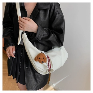 White crescent crossbody bag with a knotted strap and a brown plush poodle charm detail