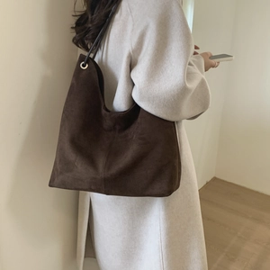 Detail of large brown suede tote bag with minimalist shoulder straps and metal eyelet accents