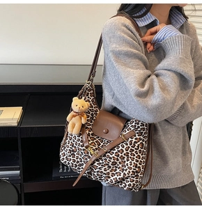 Close-up of leopard print tote bag with brown leather flap and cute plush bear charm