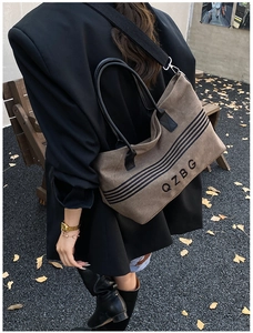 Outdoor view showing the black leather handles and detachable nylon strap of a canvas tote