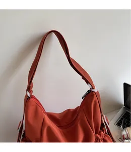 Detail of rust red crescent bag showing the long smooth shoulder strap and pleated side pocket